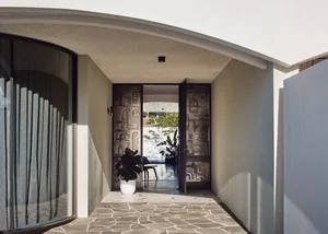 An open, modern entrance featuring a metal door and stone floor.