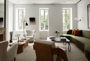 A modern living room with white walls, green sofa, and striped curtains