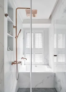 A modern minimalist bathroom featuring marble fixtures and a white bathtub with a window view.