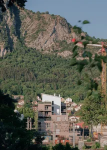 A view of buildings against a mountainous backdrop with lush greenery.