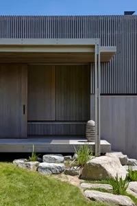 Modern exterior of a wooden house with a stone pathway and green grass.