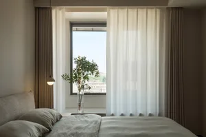 A minimalist bedroom with a bed, pillows, and curtains by the window.