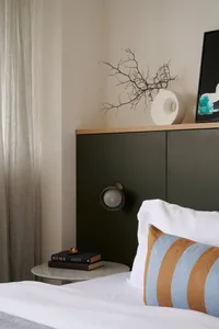 A minimalist bedroom with a textured fabric bedspread, white walls, and a green headboard.