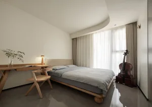 A minimalist bedroom with a wooden bed and table, featuring a Violin and white curtains on the window.