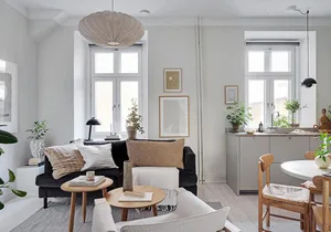 Modern minimalist living room featuring a black sofa, wooden coffee table, and white accent chairs.
