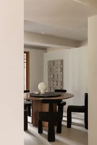 A modern interior design with a wooden dining table and black chairs.