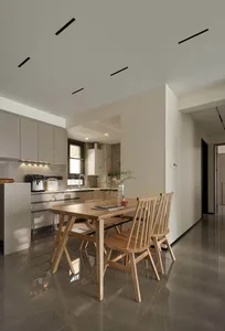 Modern kitchen with wooden table, marble countertops, and stainless steel appliances.