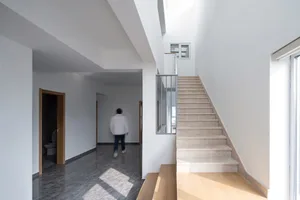 Modern stairway with marble steps surrounded by white walls and hardwood floors.