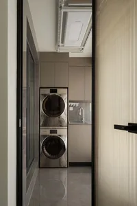 A modern minimalist laundry room featuring metallic appliances.
