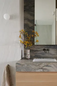 Modern minimalist bathroom featuring marble countertop and black fixtures.