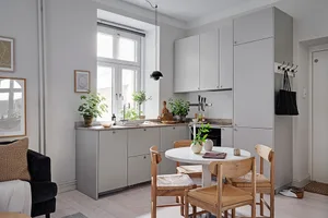 A modern minimalist kitchen with white cabinets, a round dining table, and wood chairs.