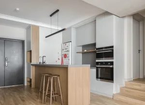 A modern residential kitchen featuring a wooden island with stools, stainless steel appliances, and light-colored cabinets.