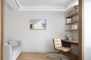 A minimalist home office with a beige leather chair and a desk, featuring a wooden floor and minimalist decor.