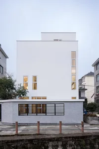 A modern building with a white facade featuring large windows and a small balcony.