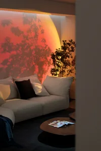 A cozy, modern living room featuring a beige sectional sofa, lush green plants, and warm, ambient lighting.