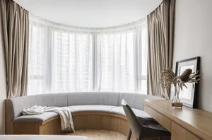 A modern living room with a curved bench seat upholstered in fabric and a wooden desk with a chair.