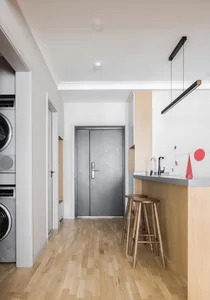 Modern minimalist kitchen featuring wooden flooring, a kitchen island with stools, and a minimalist design.