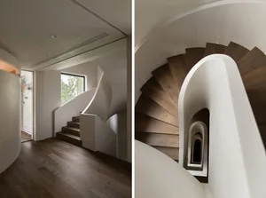 Modern minimalist staircase with curved white handrails and wooden steps, featuring natural light through a window.