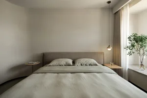 Neutral-toned minimalist bedroom with a bed, pillows, and a single hanging light fixture