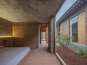 A modern bedroom with brick walls and a bed with a white sheet.