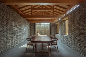 A modern industrial restaurant interior with exposed brick walls, concrete flooring, and wooden furniture.