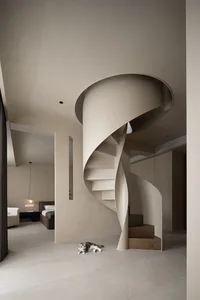 A minimalist, modern residential interior featuring a spiral staircase with light wood steps and a sleek, clean design.