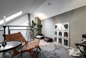 A minimalist living space with wooden furniture and a large framed architectural print on the wall.