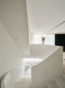 A modern spiral staircase with concrete steps and walls, featuring a minimalist design.