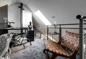 A modern home office featuring a metal desk, wooden chair, and glass balcony railing.