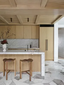 A modern kitchen featuring marble countertops and wooden cabinets.