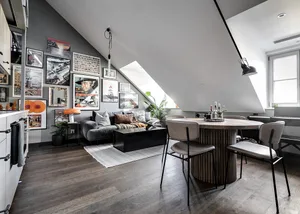 Modern, spacious living room with a dark wood floor, grey sofa, and a circular dining table with upholstered chairs.
