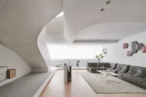 A modern living room with concrete walls, wooden flooring, and a gray textile sofa.