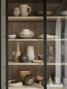 Various ceramic vessels and bowls displayed on wooden shelves in a neatly organized collection.