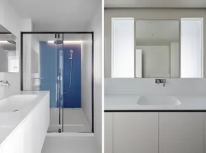 Minimalist bathroom with white and gray color scheme and glass shower enclosure.