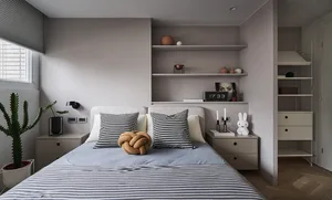 Minimalist bedroom featuring a bed with striped bedding, houndstooth pillows, and a knotted cushion, alongside a nightstand w