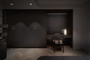 A minimalist bedroom with black furniture, wood flooring, and a desk with a light fixture.