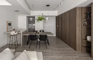 A modern living and dining room featuring a wooden table, black chairs, and a wooden shelving unit.