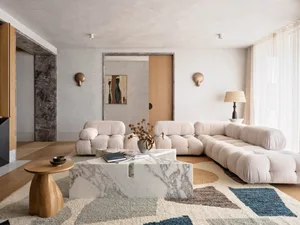 A modern living room featuring a marble sofa with leather accents and a geometric rug.