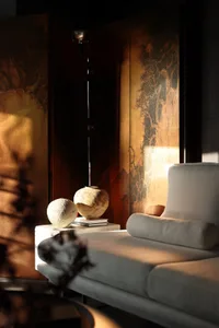 A modern living room featuring a sleek, gray fabric couch with plush cushions, a minimalist design, and decorative lighting i