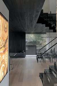 A modern living room with wooden flooring, glass railings, and a large window showcasing greenery outside.