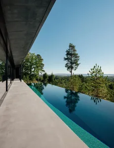 Modern luxury house with a concrete swimming pool overlooking a scenic landscape.
