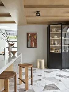 Modern kitchen with marble countertops and wooden stools and cabinets.