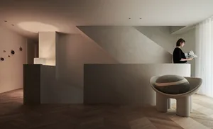 A modern, minimalist apartment featuring a concrete interior with a geometrically shaped chair.