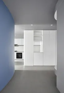 A modern, minimalist kitchen with white cabinets, concrete floor, and white walls.