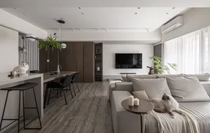 A minimalist living room with neutral-toned furniture and decor, featuring a comfortable sofa, a sleek dining area, and a fla