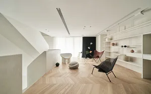 A modern residential living room with wooden flooring, minimalist furniture, and a sleek bookshelf.