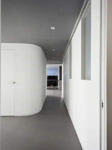 A minimalist white hallway with concrete flooring and walls, featuring a modern interior design aesthetic.