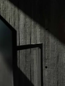 A wooden wall with a window, showcasing industrial aesthetics in black color.