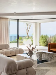 A minimalistic living room with marble furniture and a view of the ocean.