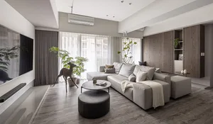 A modern living room with a gray sectional sofa, potted plants, and minimalist decor.